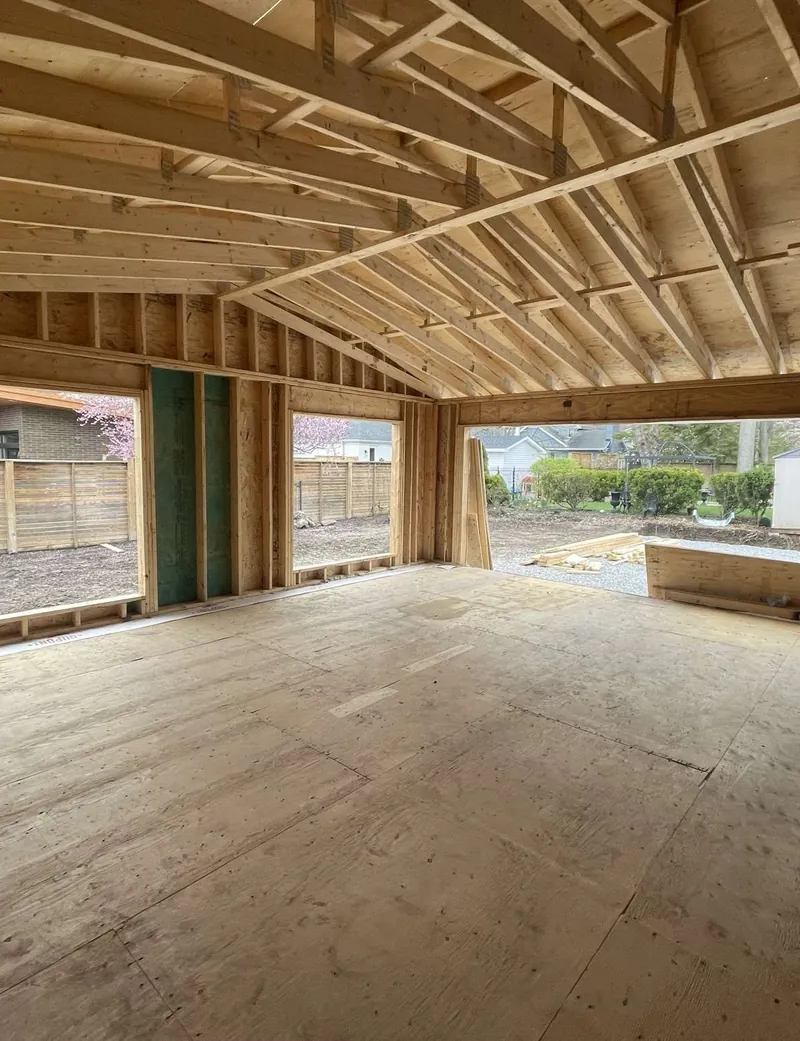 Framed home addition with open roof trusses, a new subfloor and wide window openings