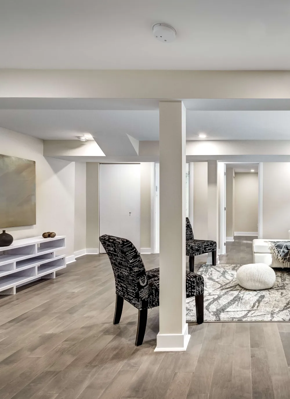 Finished basement living area with wide-plank flooring, pot lights and a seating area