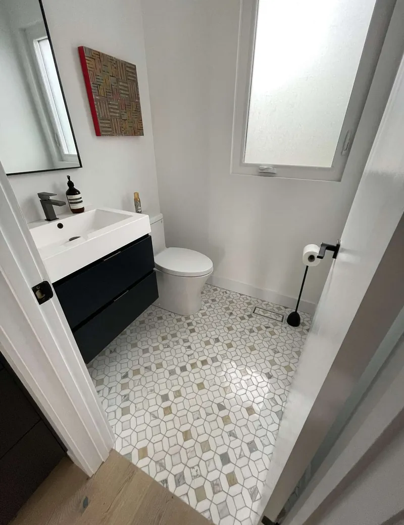 Renovated powder room with a floating black vanity, patterned floor tile and a skylight
