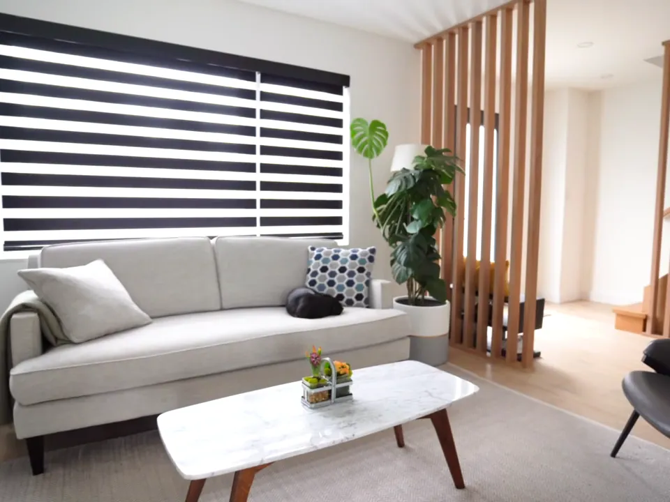 Bright renovated living room with a wood slat divider, white sofa, marble coffee table and a linear fireplace