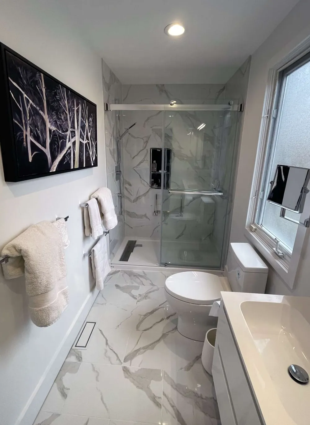 Finished bathroom with marble-look tile, a frameless glass shower and a floating vanity
